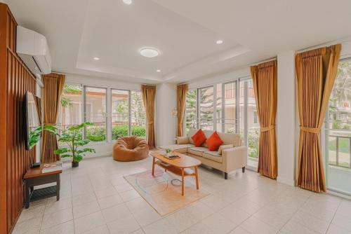 a living room with a couch and a table at Samran Beach House by May, Cha-am Beach in Cha Am
