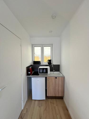 une petite cuisine avec un micro-ondes et un réfrigérateur dans l'établissement Marianne élégant studio 2p, à Séné