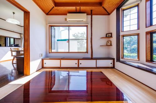 a living room with a wooden floor and windows at Fuji別邸 in Fujinomiya