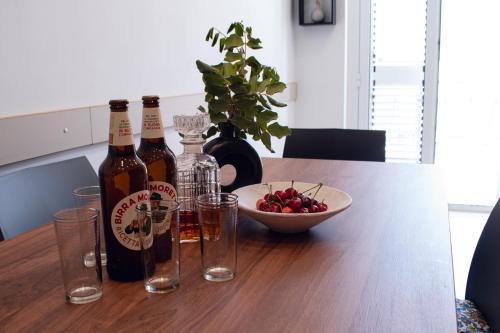 a table with bottles and glasses and a bowl of fruit at Tranquillo Rent and Experiences in Pozzallo