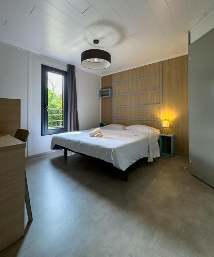 une chambre avec un grand lit blanc avec une fenêtre dans l'établissement Grand chalet familial, à Figeac