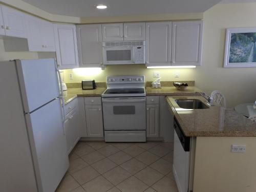 a kitchen with white cabinets and a stove and a sink at Edison Beach House in Fort Myers Beach