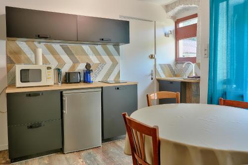 - une cuisine avec une table et un four micro-ondes dans l'établissement Joyone,appartement rénové dans maison vigneronne de 1682 avec terrasse, à Mouthier-Haute-Pierre