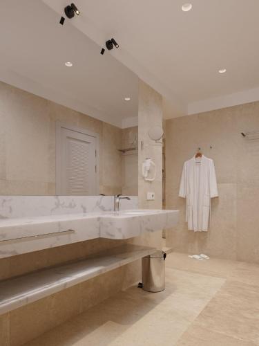 a bathroom with a sink and a white shirt hanging on the wall at Almyros Beach in Acharavi