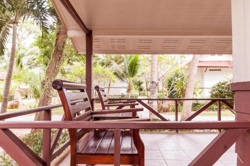 two wooden chairs sitting on a porch with palm trees at Coco Palm Beach Resort - SHA Extra Plus in Mae Nam