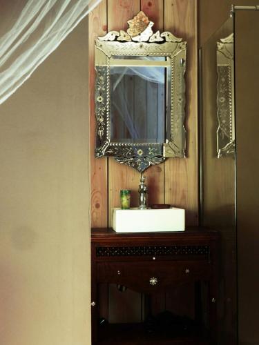 une salle de bain avec un lavabo et un miroir sur un mur dans l'établissement Gîte cosy Petit Canaillou, à Saint-André-de-Cruzières