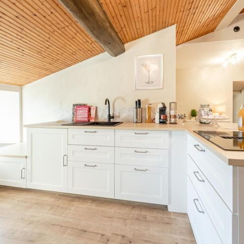 a kitchen with white cabinets and a wooden ceiling at Le Havre de Pierres, Puy du Foù in Mauléon