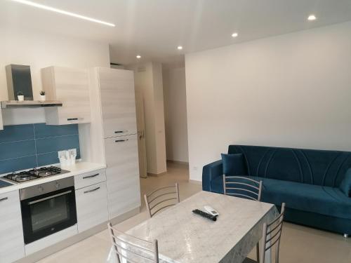a kitchen and living room with a table and a blue couch at A due passi dal mare Apartment in Capo dʼOrlando