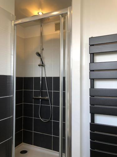 La salle de bains est pourvue d'une douche et de carrelage noir et blanc. dans l'établissement Grand appartement lumineux avec balcon, à Lorient