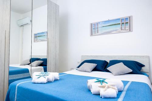 una camera da letto blu e bianca con due letti e asciugamani di Marylife vacanze - appartamento a 20 mt dal mare a Trapani
