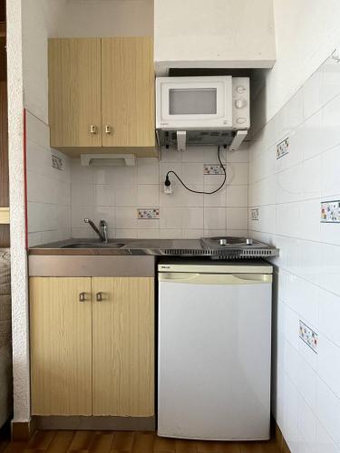 une petite cuisine avec une cuisinière et un micro-ondes dans l'établissement Studio Héliopolis F 66 - 4 personnes, au Cap d'Agde