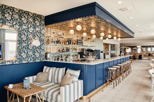 un restaurant avec un bar doté d'un canapé et de chaises dans l'établissement Hôtel de la Mer & Spa, à Brignogan-Plage