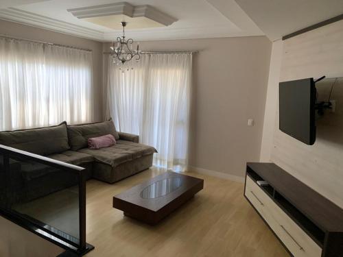 a living room with a couch and a flat screen tv at Sobrado com 5 suítes para temporada e show rural in Cascavel