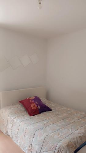 a bed with a red pillow on top of it at Maison Montfermeil T2 proche Disney, CDG et Val d'Europe in Pantin