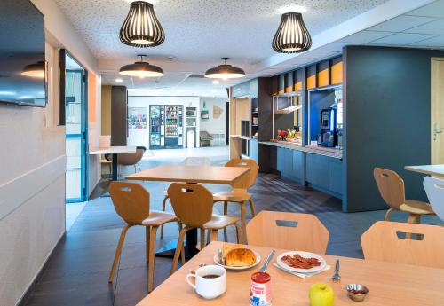 un restaurant avec deux tables et des chaises ainsi qu'une cuisine dans l'établissement B&B HOTEL Angers Parc Expos, à Saint-Sylvain-dʼAnjou