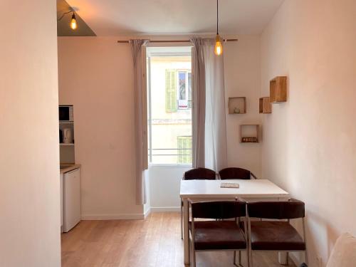 une salle à manger avec une table et des chaises et une fenêtre dans l'établissement Studio Nemausus, à Nîmes