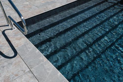 a shadow of a railing on the side of a swimming pool at Ibis Styles Dijon Nord Valmy in Dijon