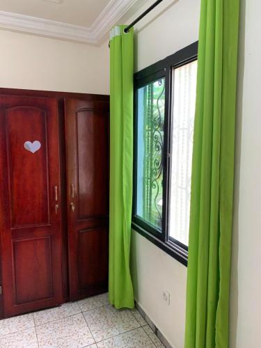 a room with green curtains and a window at Résidence Yavanie in Kribi