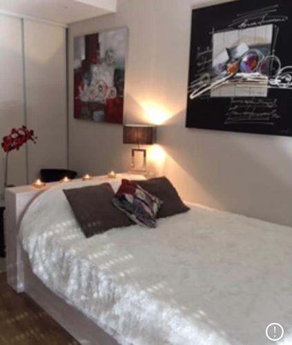 - une chambre dotée d'un lit blanc avec une photo sur le mur dans l'établissement Logement hyper centre près du Port et prés salés, à La Teste-de-Buch