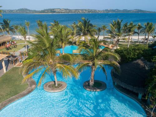 an aerial view of a resort swimming pool with palm trees at San Martinho Vila Azul in Vila Praia Do Bilene