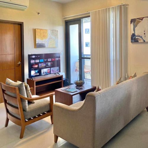 a living room with a couch and a television at One Manchester Place Mactan Newtown in Lapu Lapu City