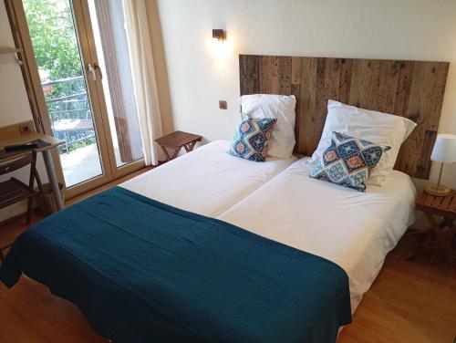 une chambre avec un grand lit blanc avec deux oreillers dans l'établissement Le Boréal, à La Bastide-de-Sérou