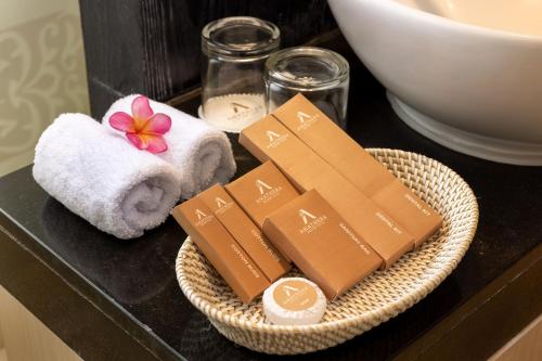 a bathroom counter with a basket of soap and towels at Anathera Resort Kuta in Kuta