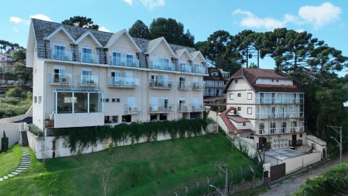 an apartment building on a hill with a green yard at Kaliman Pousada Campos do Jordão - Luxo in Campos do Jordão