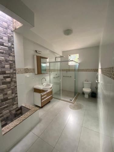 Un baño con ducha de cristal y un inodoro. en Mansão Fazendinha para grupos Arraial do Cabo, en Arraial do Cabo