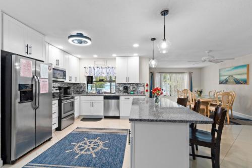 a kitchen with white cabinets and a large island with a table at 5 Bed Heated Pool Largo, Seminole FL 2 mi Indian Rocks Beach , Pets, Game room in Seminole