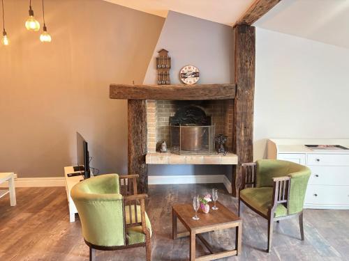 Una sala de estar con chimenea y sillas verdes. en Cosy loft in Saint Emilion, en Saint-Émilion