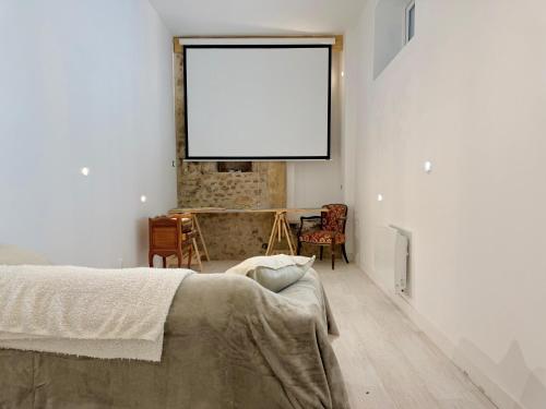 - une chambre avec un lit et un écran blanc sur le mur dans l'établissement Grand appartement centre-ville, à Poitiers