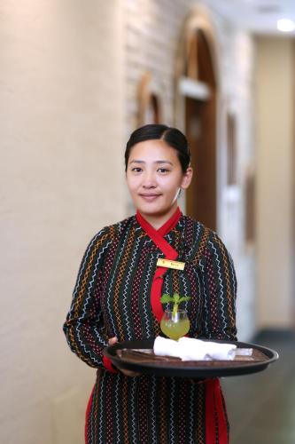 a woman holding a tray with a drink on it at Temple Bell Boutique Hotel & Spa in Pokhara
