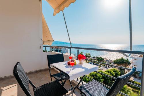 a balcony with a table and chairs and the ocean at Roan Apartments in Sarandë