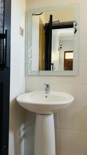 a bathroom with a white sink and a mirror at African Jacana Inn and Camps in Mto wa Mbu