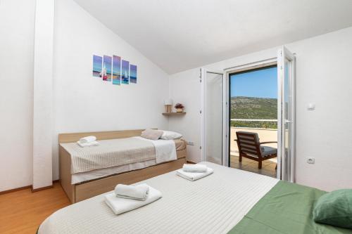 a bedroom with two beds and a chair and a balcony at Peacefull getaway island Hvar! in Selca kod Starigrada