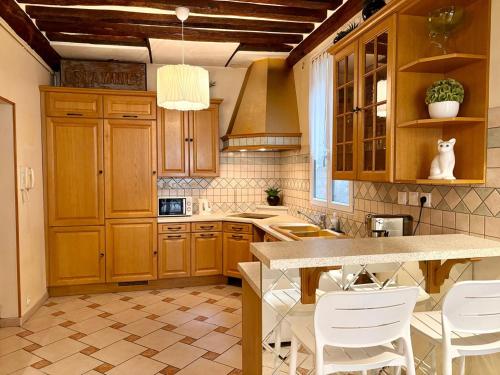 - une cuisine avec des placards en bois et des chaises blanches dans l'établissement Appartement Central St Germain, à Paris