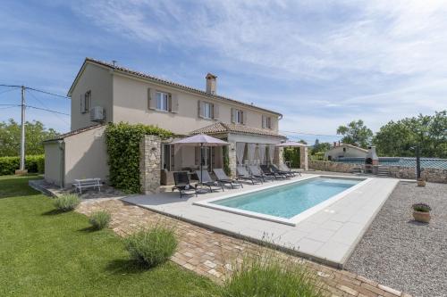 an external view of a house with a swimming pool at Villa Batelica with large garden, kids playground and private pool in Labin