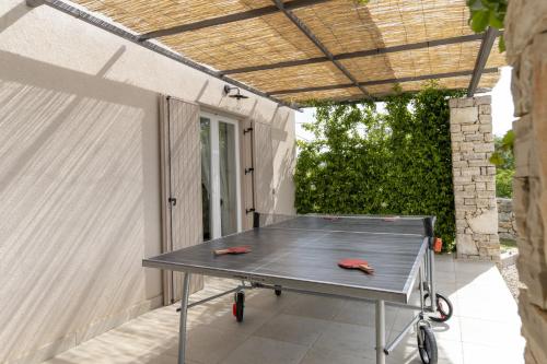 a ping pong table on a patio with awning at Villa Batelica with large garden, kids playground and private pool in Labin