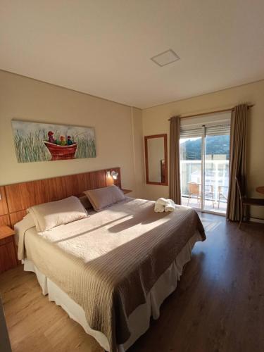 a bedroom with a large bed and a window at Kaliman Pousada Campos do Jordão - Luxo in Campos do Jordão