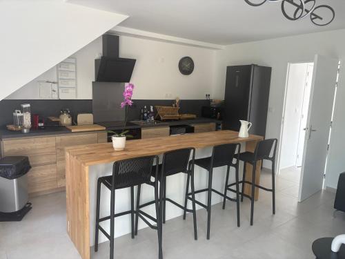 - une cuisine avec un comptoir en bois et des tabourets de bar noirs dans l'établissement Villa Champan, à La Ciotat