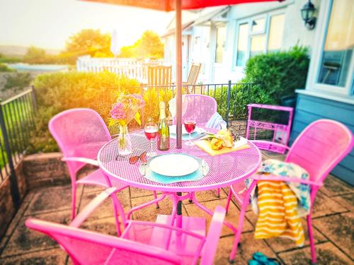 a pink table and chairs on a patio at Dart Haven - cheerful holiday bungalow in Galmpton in Galmpton-on-the-Dart