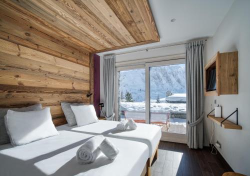 une chambre avec deux lits et une grande fenêtre dans l'établissement Chalet Ancolie, à Tignes