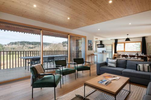 a living room with a couch and a table at Chalet L'Urson, spacieux, jacuzzi, hammam et sauna in Gérardmer