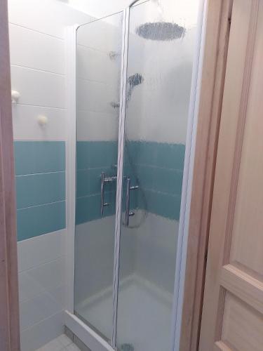 une douche avec une porte vitrée dans une salle de bain dans l'établissement Maison du Centre, à Saint-Jean-de-Monts
