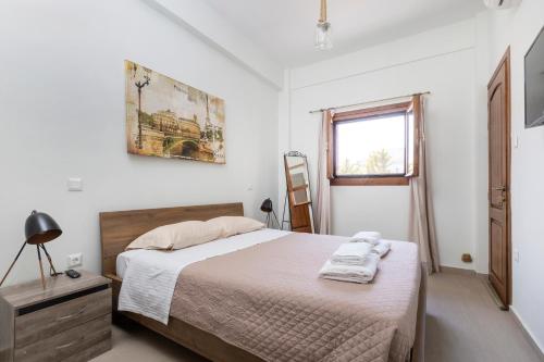 a white bedroom with a bed and a window at Utopia suites in the heart of Aegina by 8essentially in Aegina Town