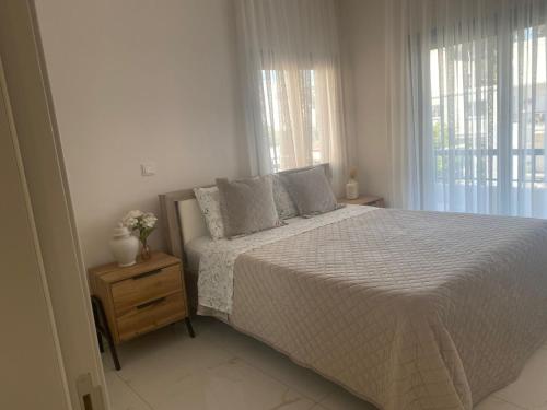 a white bedroom with a bed and a window at Kyra apartment in Polis Chrysochous