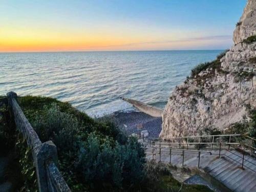 a staircase leading down to the ocean at sunset at LE CISE EAU À bois in Le Bois de Cise