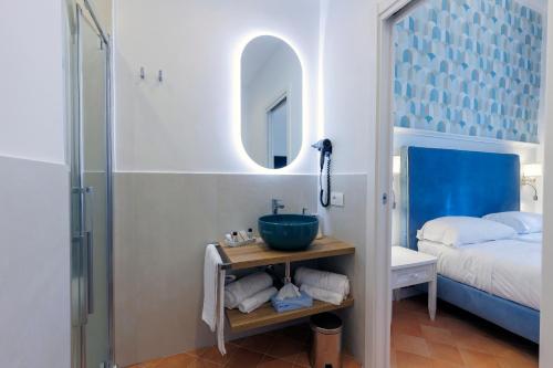 a bathroom with a sink and a bed and a mirror at D'Amalfi Hospitality in Amalfi