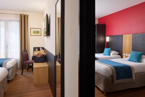 a hotel room with two beds and a red wall at Hôtel Roissy in Lourdes